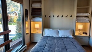 A hotel room with a bed, two bedside tables with lamps, a mirror, and a wall with a forest decal. - Ski-In/Ski-out  - 50 ft from SuperBee Lift (Copper Mountain)
