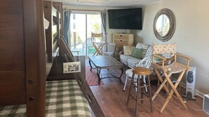 Uma sala de estar com sofá, cadeiras, uma mesa e uma televisão.