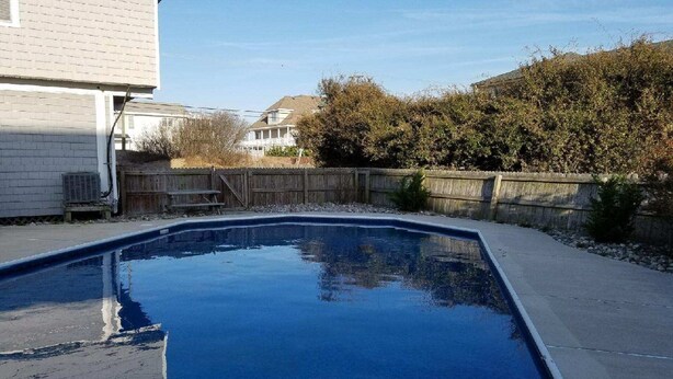 Uma piscina retangular com um deck de madeira ao redor.