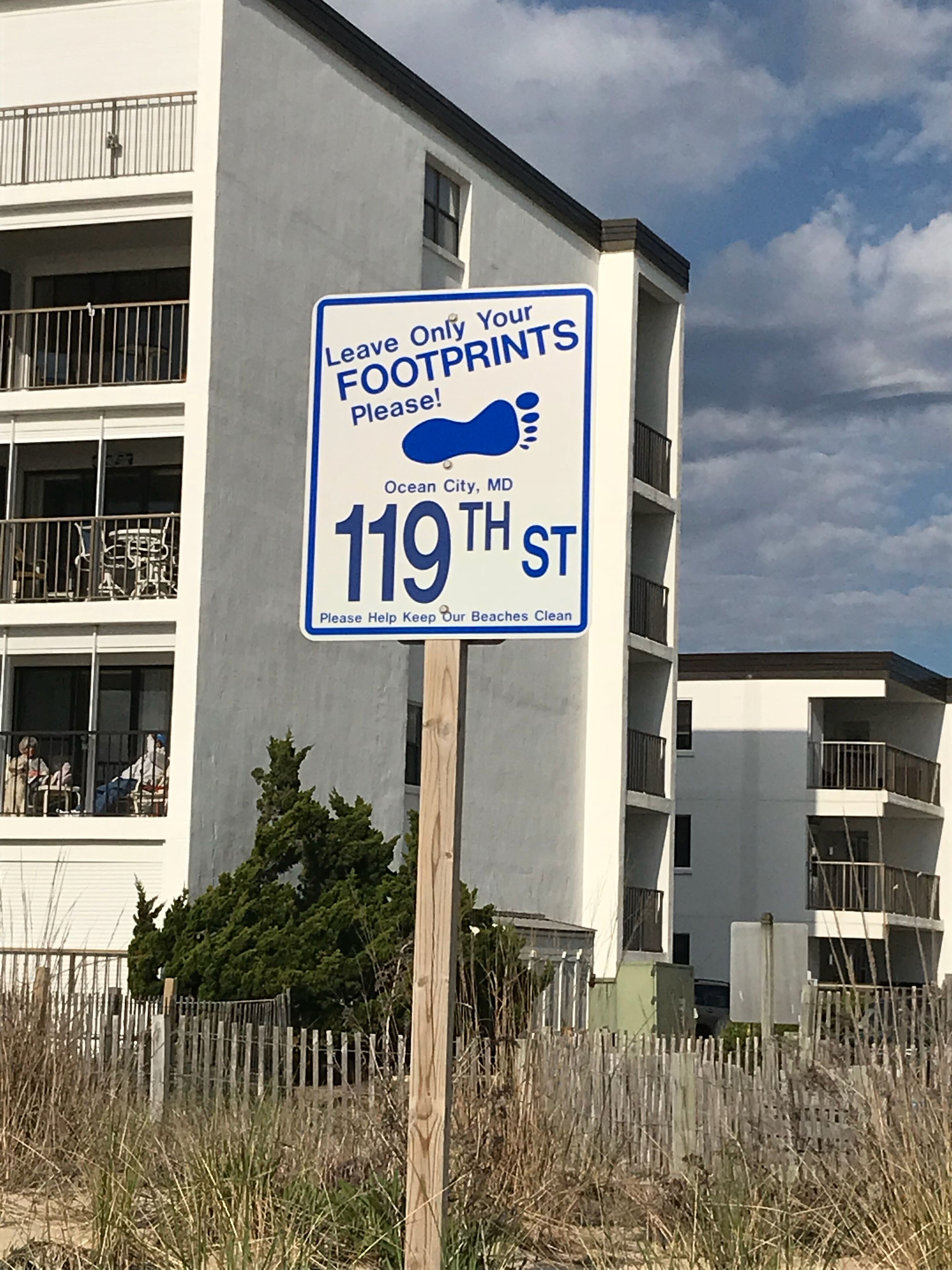Une pancarte fixée à un poteau en bois, portant un message sur les empreintes et une adresse.