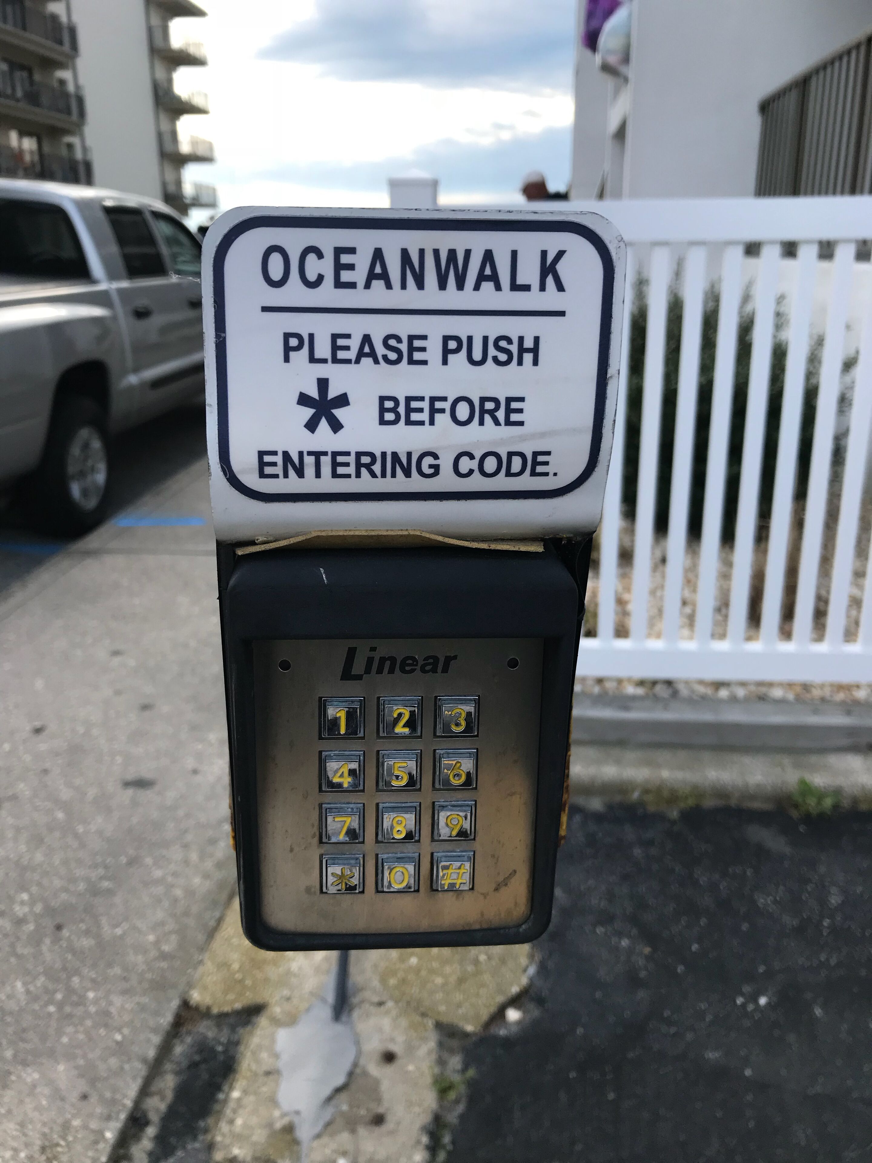 A parking meter with a sign above it that reads 'OCEANWALK PLEASE PUSH BEFORE ENTERING CODE.'