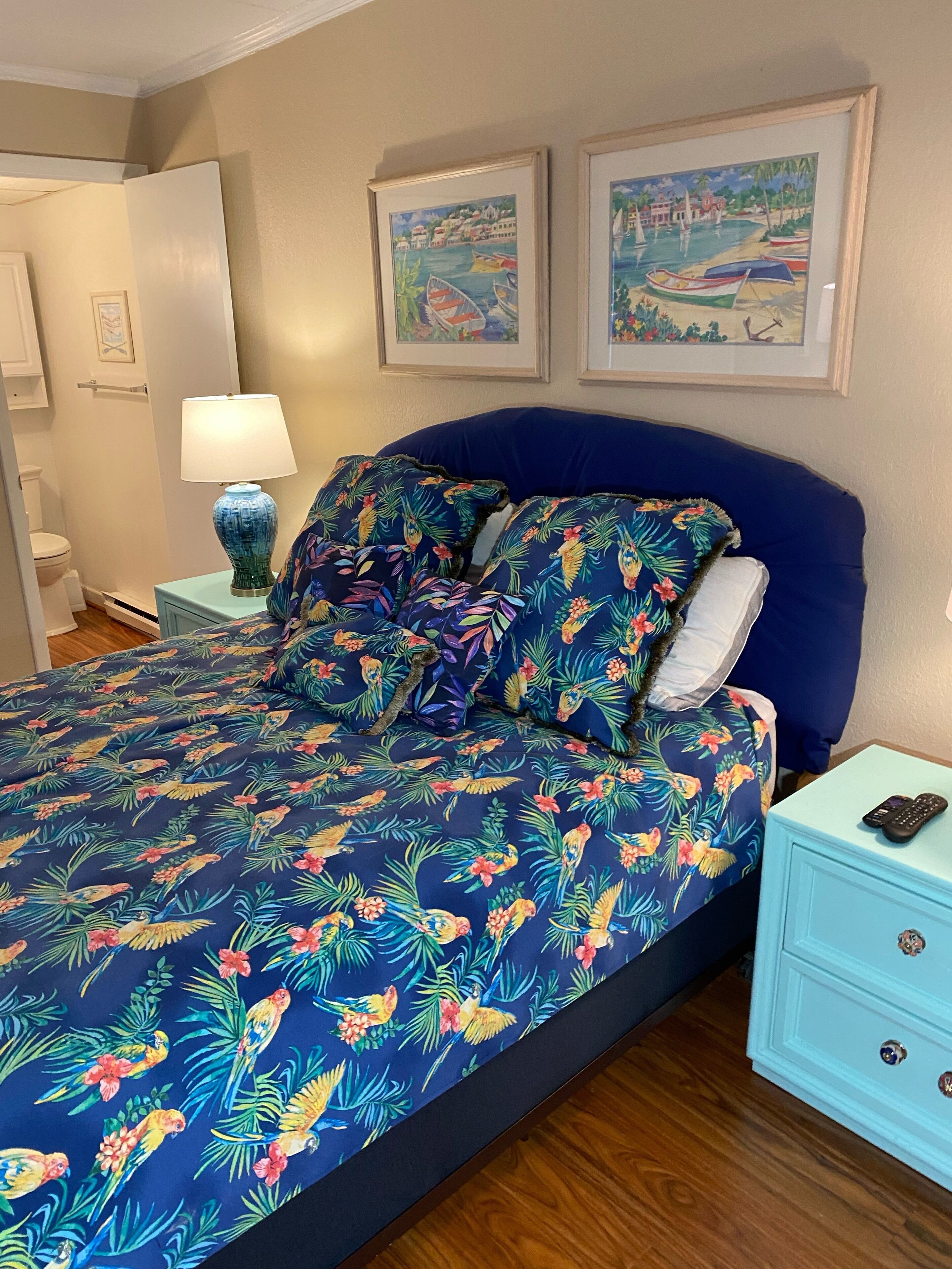 A bedroom with a bed, a nightstand, a lamp, and two framed pictures on the wall.