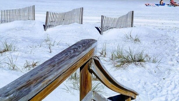 A wooden boardwalk leading to a beach with a clear view of the ocean.