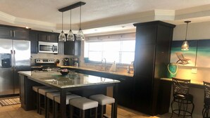 Een moderne keuken met een groot eiland, donkere kasten en hanglampen.