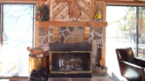 Un intérieur rustique avec une cheminée en pierre, des poutres en bois et de grandes fenêtres.
