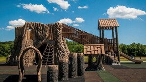 Une aire de jeux avec une structure d’escalade en bois et un toboggan.