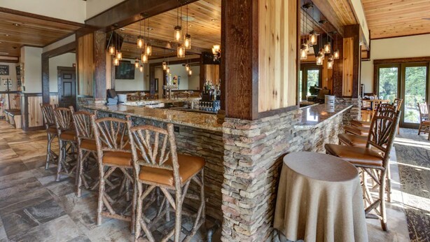 Un vaste espace bar agrémenté d’éléments en pierre, de chaises en bois et de luminaires suspendus.