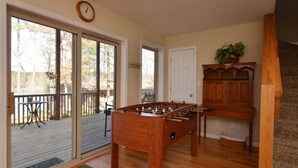 Una sala acogedora con mesa de futbolín de madera, una mesa de comedor y una escalera.