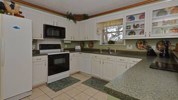 A kitchen with white cabinets, a microwave, stove, and a sink.