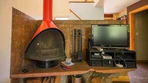 Ein modernes Wohnzimmer mit Kamin aus Stein, einem Fernseher und Kaminwerkzeug.