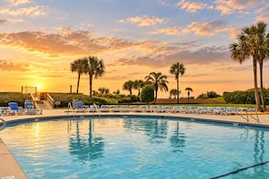 A swimming pool with lounge chairs and palm trees, surrounded by a landscaped area. - Beautiful Ocean Views, Beach Club 337! Steps to beach! (St. Simons Island)