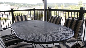 A covered outdoor patio with a round metal table and striped cushioned chairs.