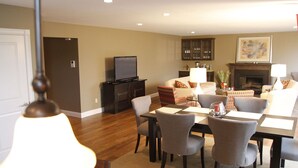 A living room with a fireplace, a television, and a dining area with a table and chairs.