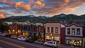 A street lined with historic buildings, a road with parked cars, and mountains in the background. - Pine Ridge Ski-In Condo on Four O'Clock Ski Run - 1 block from Downtown (Breckenridge)