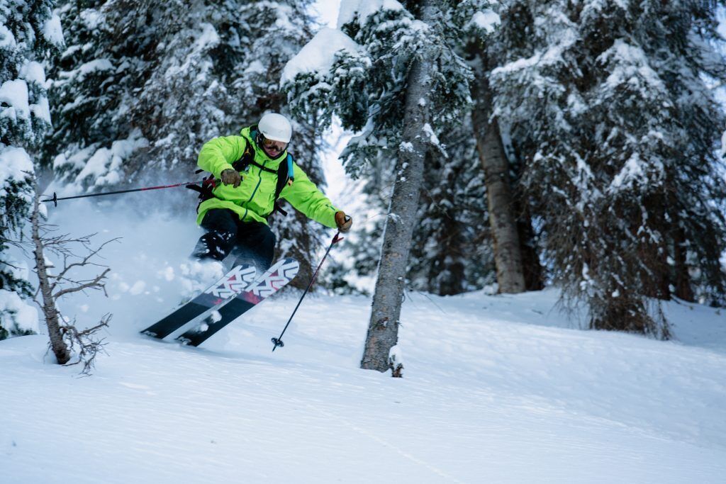 A person skiing down a snowy slope with trees in the background.