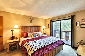 A bedroom with a bed, two bedside tables, a nightstand, a window with a view, and a wooden headboard. - Pine Ridge Ski-In Condo on Four O'Clock Ski Run - 1 block from Downtown (Breckenridge)