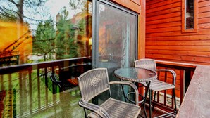 A wooden exterior with a glass door and windows, wicker chairs, and a small round table on a balcony. - Pine Ridge Ski-In Condo on Four O'Clock Ski Run - 1 block from Downtown (Breckenridge)