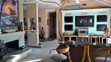 A living room with a fireplace, a dining area with a bar, and a TV wall.