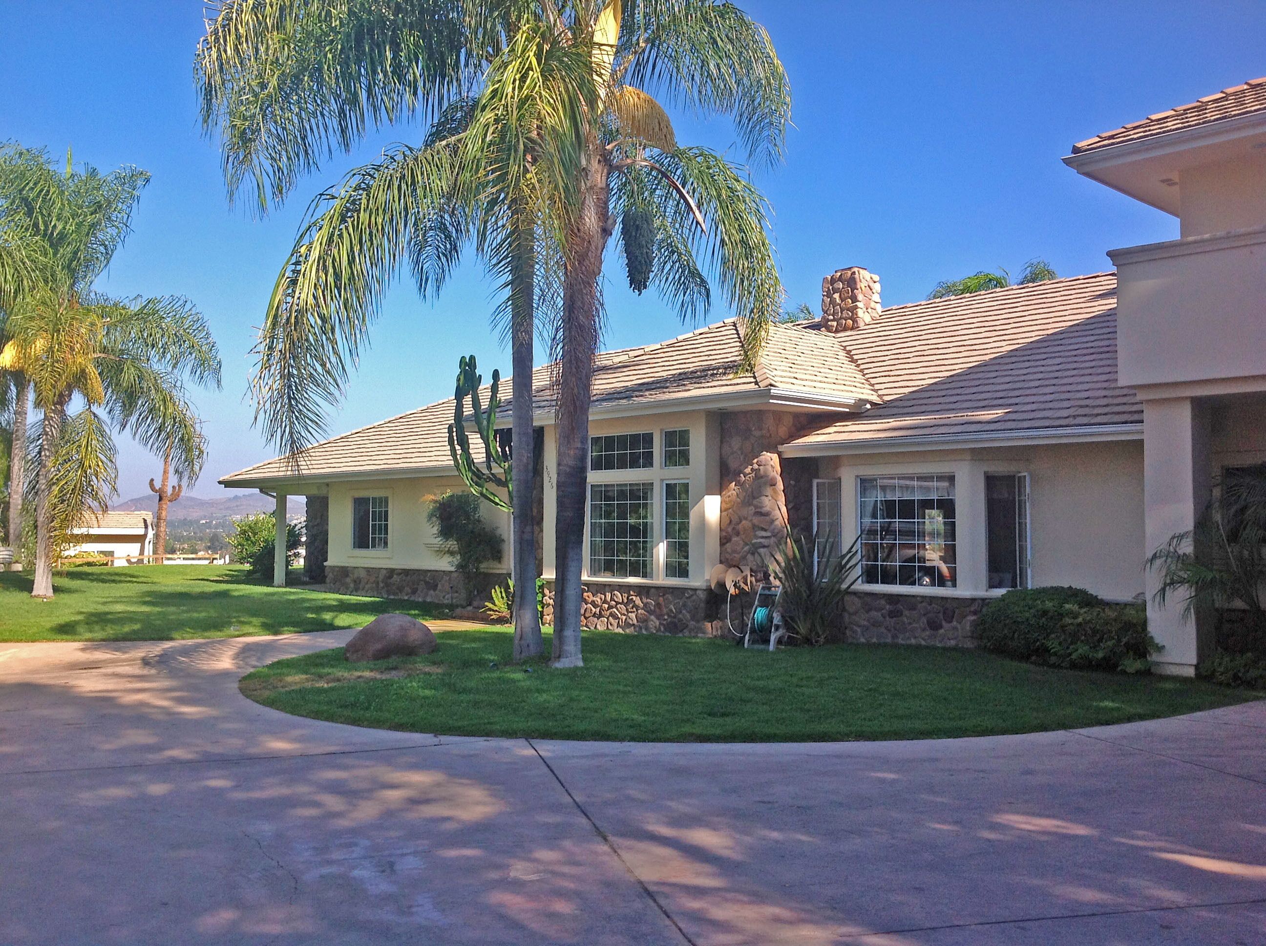 A residential house with a stone facade, large windows, and a well-maintained lawn.