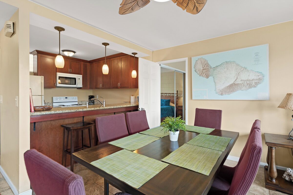 A modern kitchen with wooden cabinets, a microwave, and a dining area with a large table and chairs.