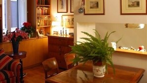 Un cuarto acogedor con techo de madera, una estantería llena de libros, una mesa de comedor con sillas y una planta en maceta.