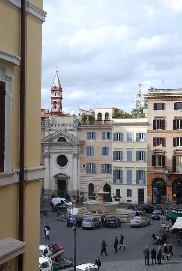 A square with historic buildings, a fountain, and a clock tower.