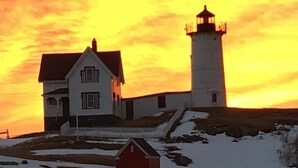 A lighthouse with a white house beside it, both with snow on the ground. - Gorgeous 6 Bedroom Ocean Front Home steps from Short Sands (York)