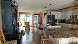 A kitchen with a central island, bar stools, and a dining area with chairs. - Gorgeous 6 Bedroom Ocean Front Home steps from Short Sands (York)