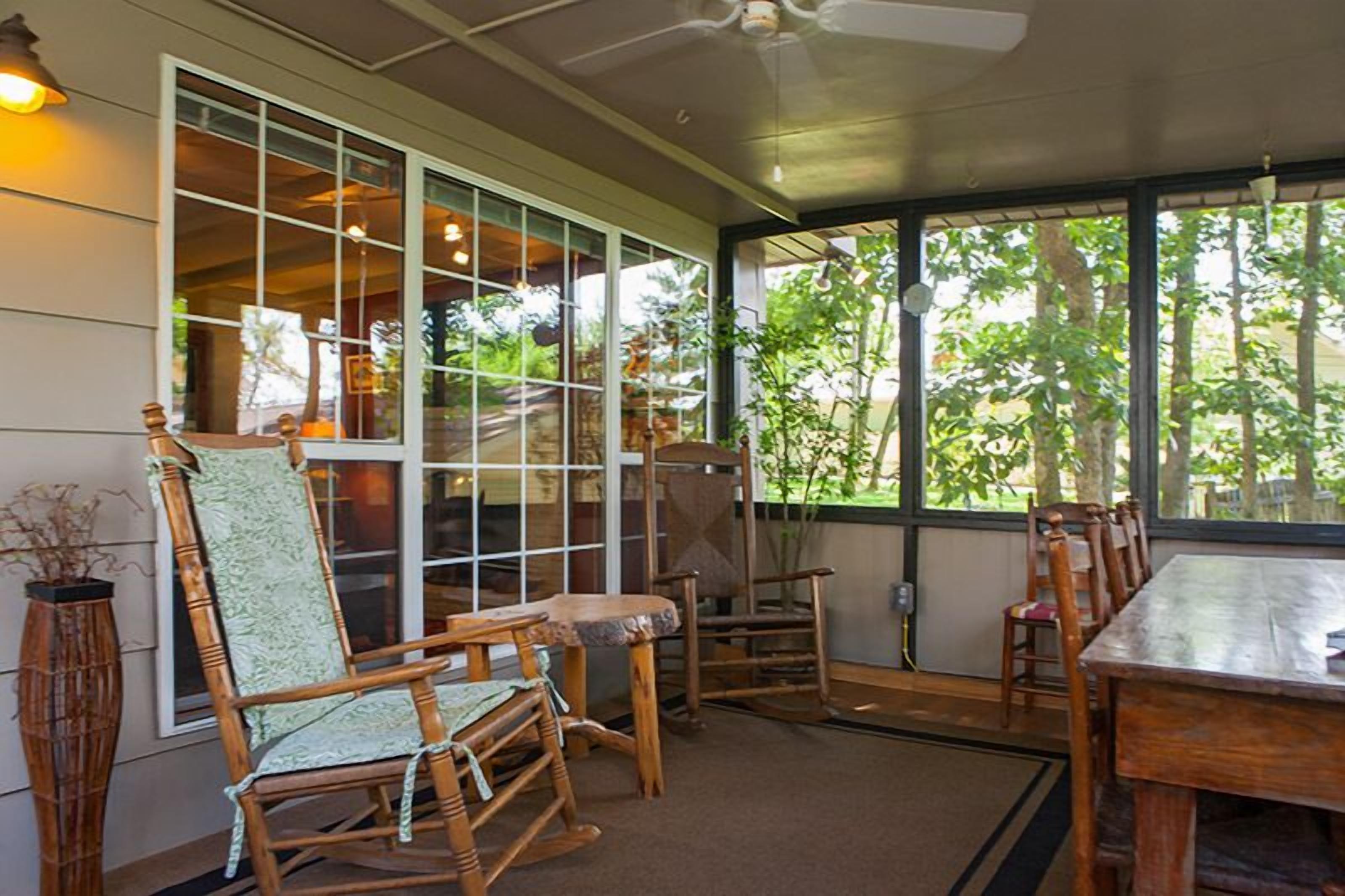 A room with a large window, wooden furniture, and a ceiling fan.