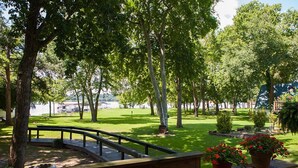 Ein Park mit einer gebogenen Holzbank, einer kleinen Brücke und Topfpflanzen.