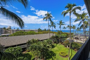 A residential area with a view of the ocean, palm trees, and a building with a sloped roof. - 5th Floor Oceanview Retreat Steps from the Beach (Kihei)