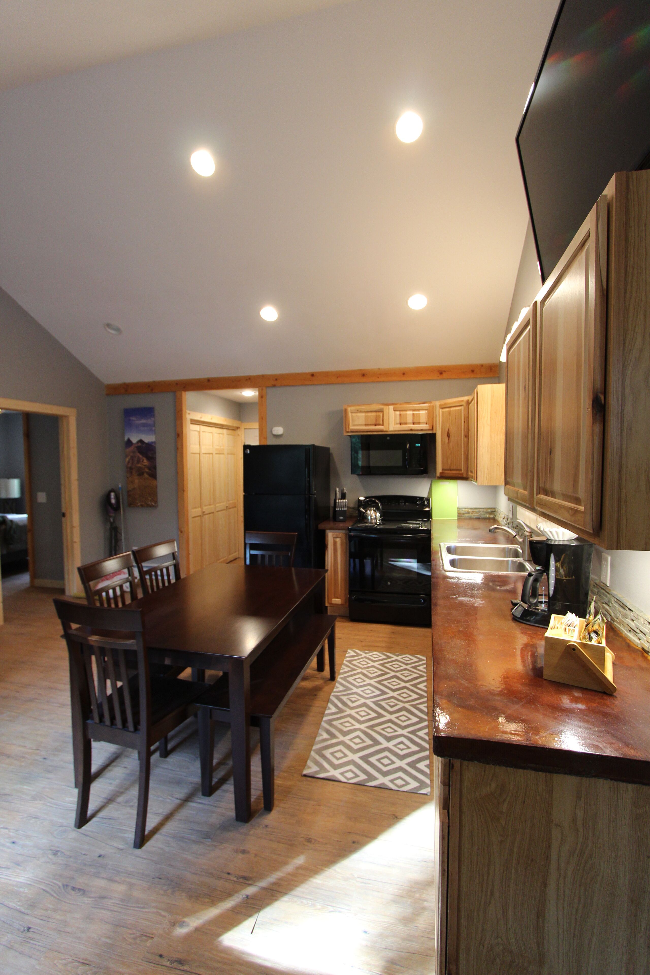 A modern kitchen with wooden cabinets, a dining table, and a black refrigerator.