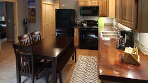 A modern kitchen with wooden cabinets, a dining table, and a black refrigerator.