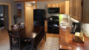 A modern kitchen with wooden cabinets, a dining table, and a black refrigerator.