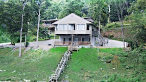 A two-story house with a balcony, a staircase leading to the second floor, and a view of a body of water.