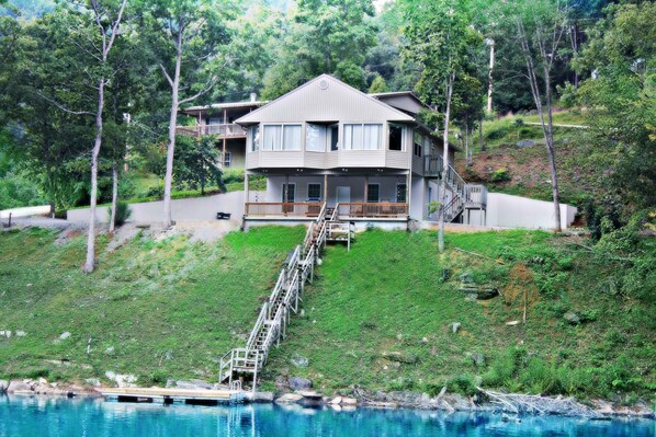 Une maison à deux étages avec un balcon, un escalier menant à l’étage supérieur et une vue sur une étendue d’eau.