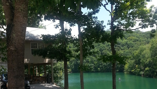 A gravel path leading to a house with a dock extending into a lake, surrounded by trees.