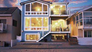 A two-story house with a balcony, large windows, and a staircase leading to the upper floor.