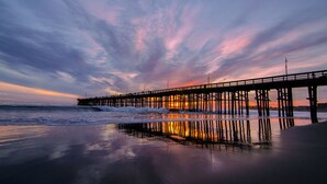 A pier extending into the water with a sunset in the background.