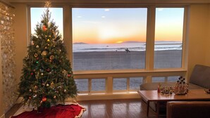 A room with a Christmas tree, a view of the beach, and a table with figurines.
