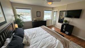 Ein Schlafzimmer mit Bett, Schreibtisch, Fernseher und einem Fenster mit Blick.