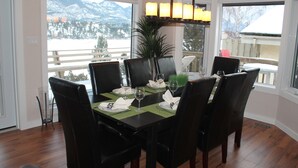 Ein Esszimmer mit Tisch für sechs Personen, großen Fenstern mit Blick auf die Berge und einer Chandelier.