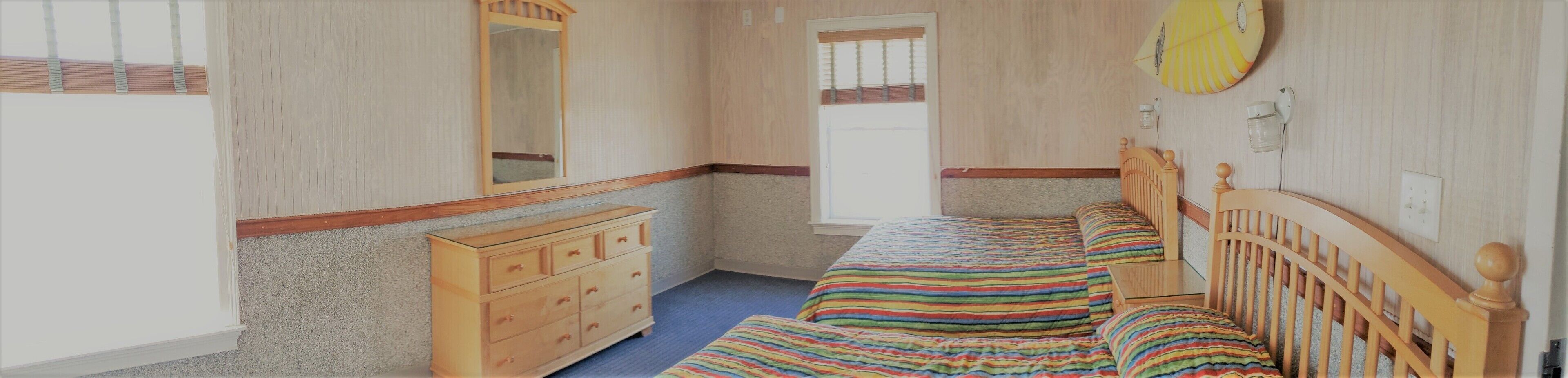 Una camera da letto con un letto, una cassettiera e una finestra.