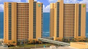 Un hotel amb diversos edificis alts, vistes a la platja i un pont per a vianants.