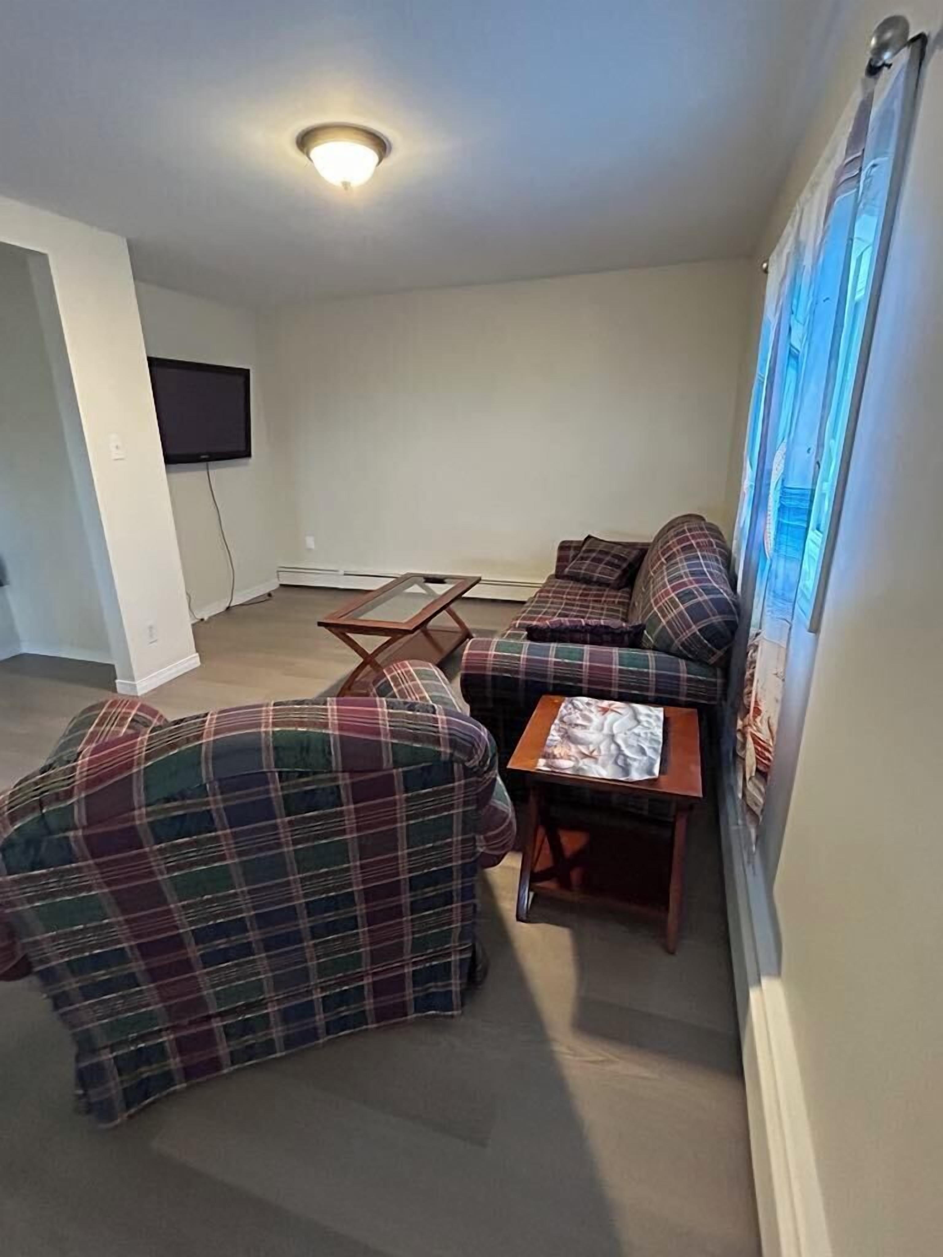 A living room with a sofa, a coffee table, and a flat-screen TV mounted on the wall.