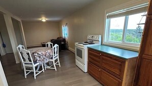 A compact kitchen with a dining area, wooden cabinets, and a window with a view. - Whale Cove suites (Whale Cove)