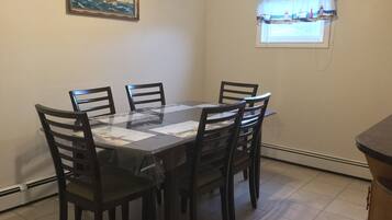 Un comedor con una mesa rectangular y seis sillas, un cuadro en la pared y una ventana con vistas al mar.