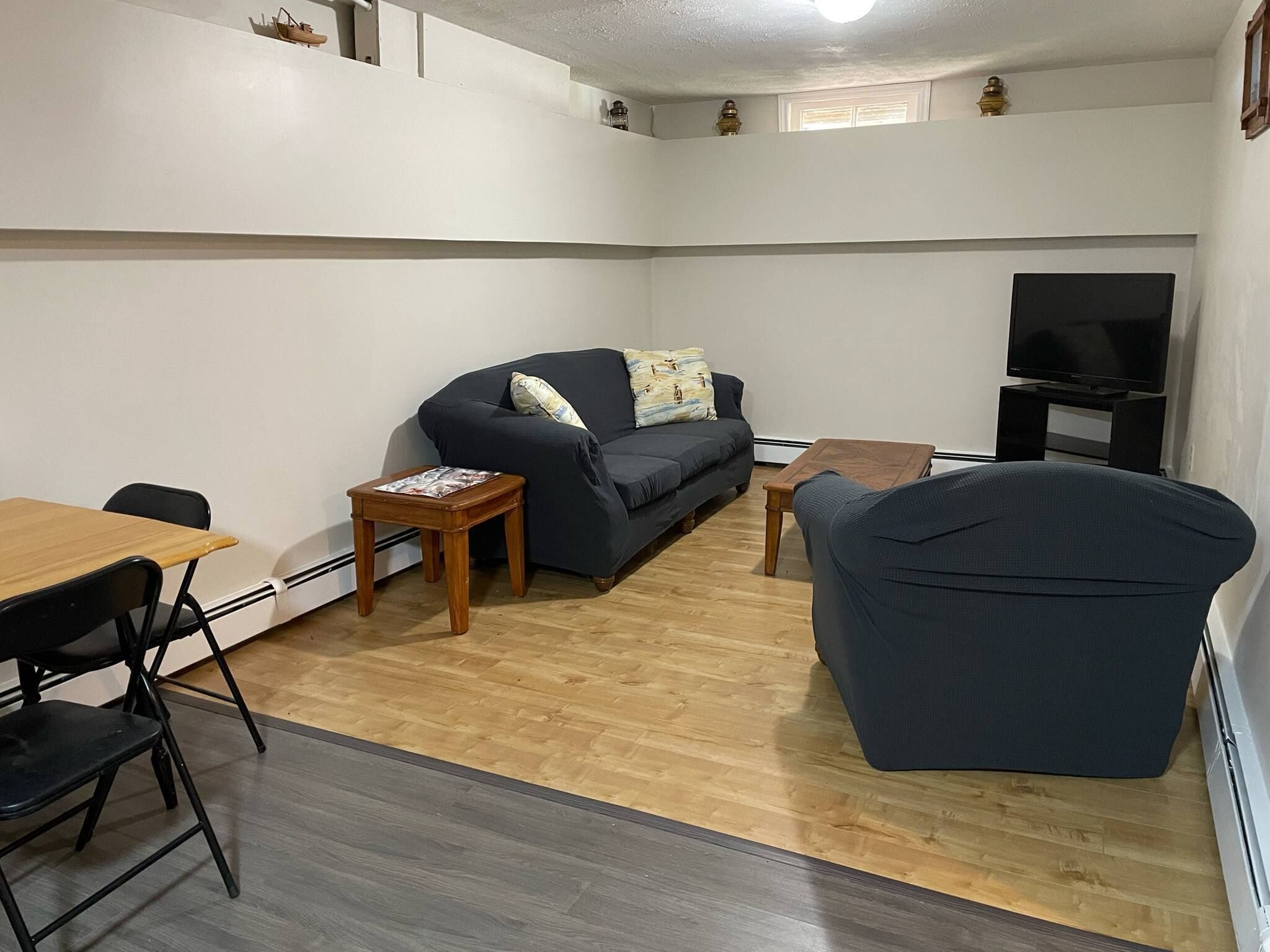 A living room with a sofa, a TV, a wooden coffee table, and a small side table.