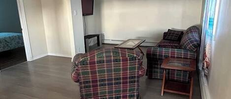 A spacious living area with a sofa set, a small table, and a television.