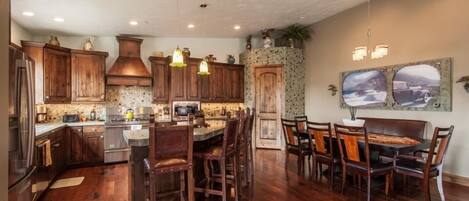 A spacious kitchen with wooden cabinets, a central island, and a dining area with chairs and a table.